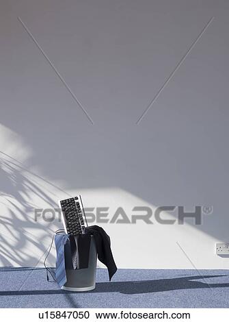 Stock Image - Computer keyboard and suit in waste bin. Fotosearch