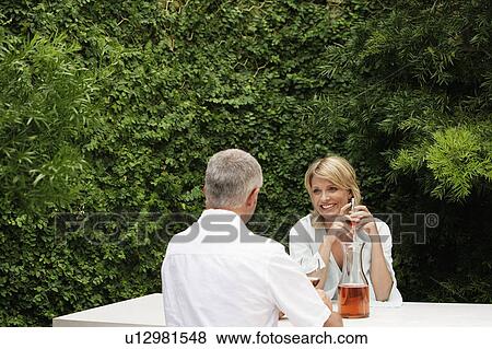 Couple drinking wine, sitting at outdoor table View Large Photo Image Stock Photo - Couple drinking wine, sitting at outdoor table. Fotosearch