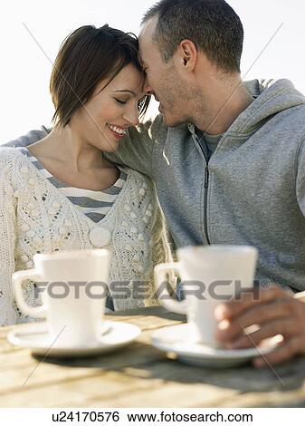 Couple embracing, sitting at outdoor table, half length View Large Photo Image Stock Photograph - Couple embracing, sitting at outdoor table, half length. Fotosearch