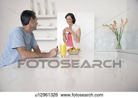 Couple having breakfast at kitchen bench View Large Photo Image Stock Photograph - Couple having breakfast at kitchen bench. Fotosearch