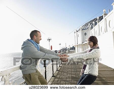 Couple holding hands, spinning around on deck of pier View Large Photo Image Stock Photo - Couple holding hands, spinning around on deck of pier. Fotosearch