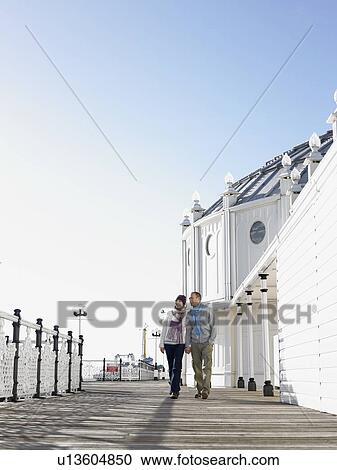 Couple holding hands, walking along pier View Large Photo Image Stock Image - Couple holding hands, walking along pier. Fotosearch