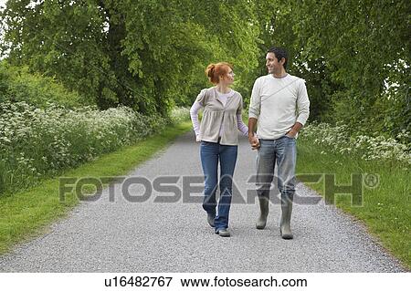 Couple holding hands, walking on country lane View Large Photo Image Stock Photo - Couple holding hands, walking on country lane. Fotosearch