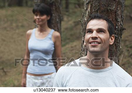 Couple in Forest Leaning on Trees, man looking up at canopy View Large Photo Image Stock Photo - Couple in Forest Leaning on Trees, man looking up at canopy. Fotosearch