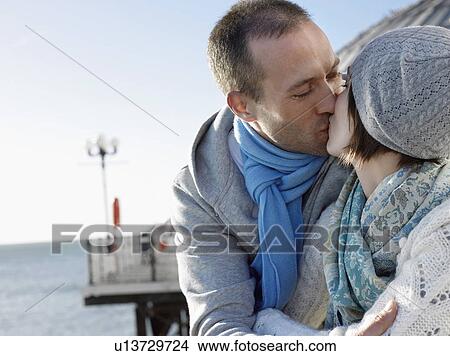 Picture - Couple kissing, standing on pier, head and shoulders. Fotosearch