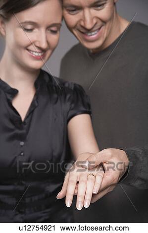 Couple looking at engagement ring on woman's hand View Large Photo Image Stock Image - Couple looking at engagement ring on woman's hand. Fotosearch