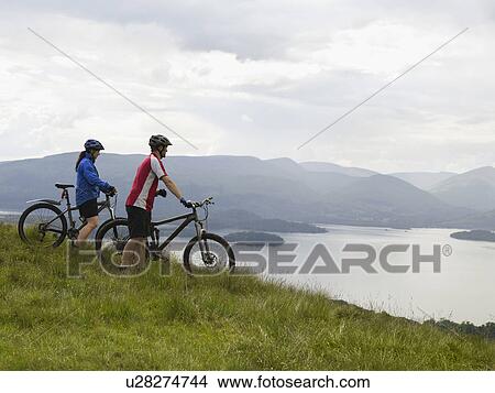 Couple on bicycles near lake View Large Photo Image Picture - Couple on bicycles near lake. Fotosearch