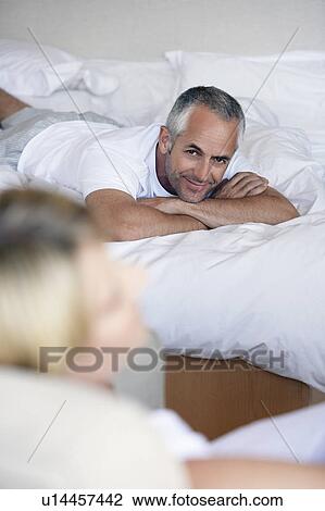Couple relaxing in bedroom, elevated view View Large Photo Image Stock Image - Couple relaxing in bedroom, elevated view. Fotosearch