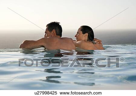 Couple relaxing in infinity pool at sunset, back view View Large Photo Image Stock Photography - Couple relaxing in infinity pool at sunset, back view. Fotosearch