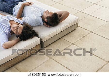 Couple relaxing on sun beds on terrace, elevated view View Large Photo Image Stock Image - Couple relaxing on sun beds on terrace, elevated view. Fotosearch