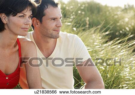 Couple Sitting in tall grass looking out at view, portrait View Large Photo Image Stock Photograph - Couple Sitting in tall grass looking out at view, portrait. Fotosearch