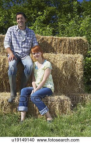 Couple sitting on hay bales in countryside, portrait View Large Photo Image Stock Image - Couple sitting on hay bales in countryside, portrait. Fotosearch
