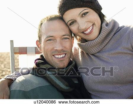 Couple sitting together on deck chair on beach, portrait View Large Photo Image Stock Photograph - Couple sitting together on deck chair on beach, portrait. Fotosearch