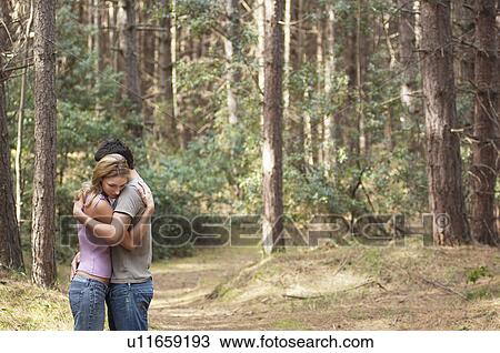 Stock Image - Couple standing on forest trail Hugging, side view. Fotosearch