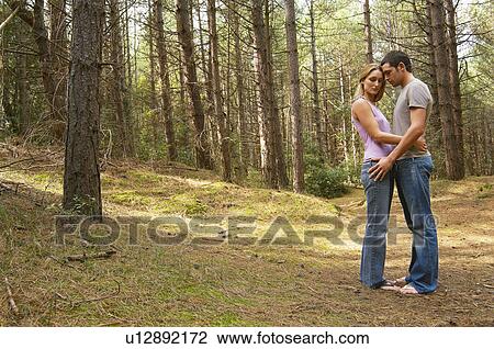 Stock Image - Couple standing on forest trail Hugging, side view. Fotosearch