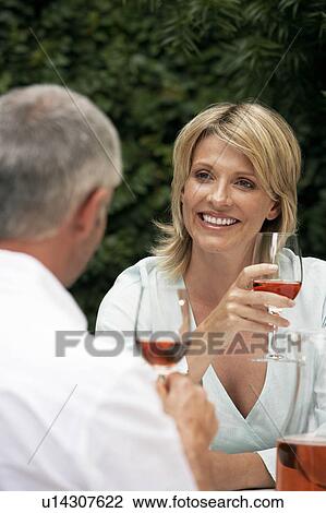 Stock Image - Couple talking, drinking wine outdoors. Fotosearch