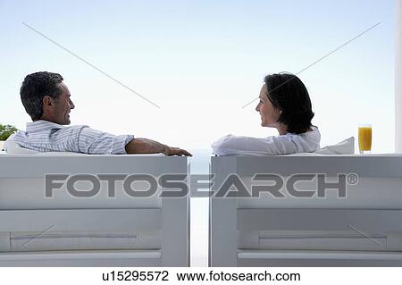 Couple talking, sitting on lounge chairs, outdoors View Large Photo Image Stock Image - Couple talking, sitting on lounge chairs, outdoors. Fotosearch