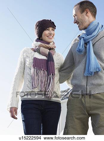 Couple walking arm in arm on pier, low angle view View Large Photo Image Picture - Couple walking arm in arm on pier, low angle view. Fotosearch