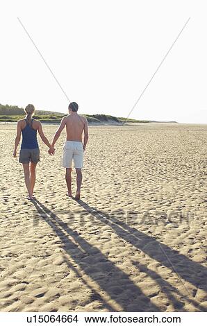 Picture - Couple Walking on Beach holding hands, back view. Fotosearch