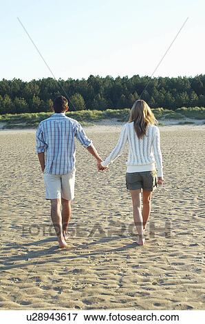 Couple Walking on Beach holding hands, back view View Large Photo Image Stock Photo - Couple Walking on Beach holding hands, back view. Fotosearch