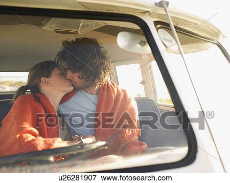 Stock Photo - Couple wrapped in blanket, kissing, in front seat of van, view through windscreen. Fotosearch