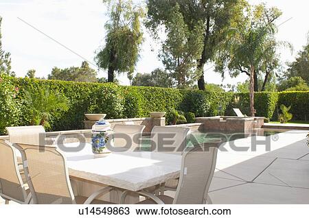 Stock Image - Cream dining furniture at poolside. Fotosearch