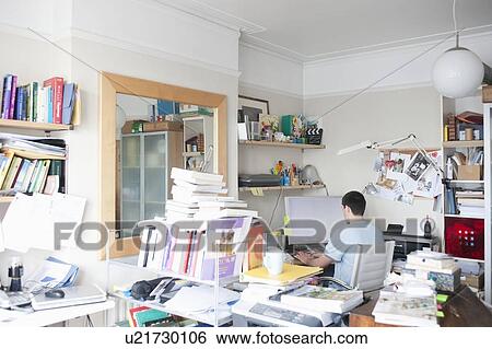 Stock Photograph - Creative professional sits at computer in corner of office. Fotosearch