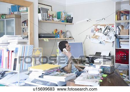 Stock Image - Creative professional sits on phone in corner of office. Fotosearch