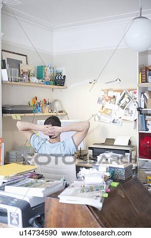 Stock Image - Creative professional sits with hands behind head. Fotosearch