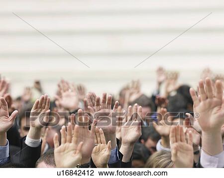 Stock Image - Crowd of people raising hands, focus on hands. Fotosearch