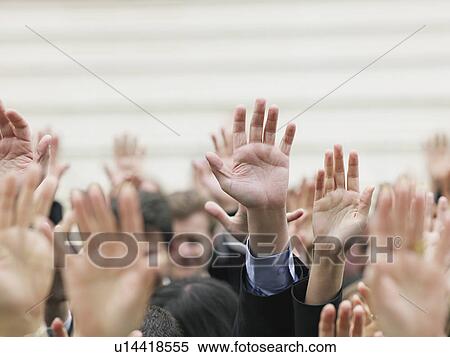 Stock Photography - Crowd of people raising hands, focus on hands. Fotosearch