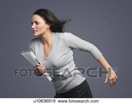Stock Photo - Determined Young Businesswoman, leaning into wind. Fotosearch
