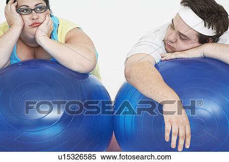 Disinterested overweight man and woman lying on Exercise Balls, close up View Large Photo Image Stock Photography - Disinterested overweight man and woman lying on Exercise Balls, close up. Fotosearch