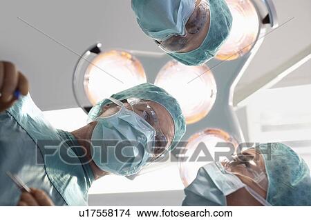 Doctors in surgery discussing surgery procedure, personal perspective View Large Photo Image Picture - Doctors in surgery discussing surgery procedure, personal perspective. Fotosearch