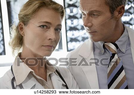 Stock Image - Doctors standing by brain scan images, portrait of woman. Fotosearch