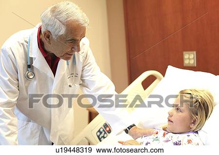 Elderly doctor leans over patient in pediatrics ward View Large Photo Image Stock Photo - Elderly doctor leans over patient in pediatrics ward. Fotosearch