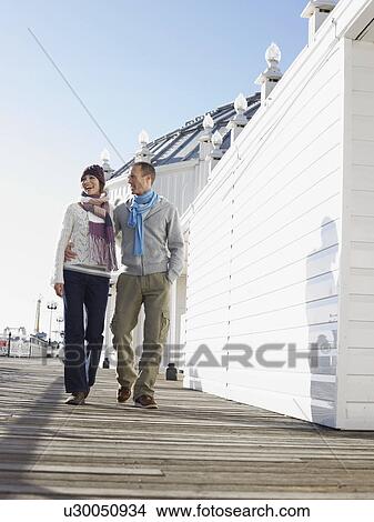 Picture - Embracing couple walking along pier. Fotosearch