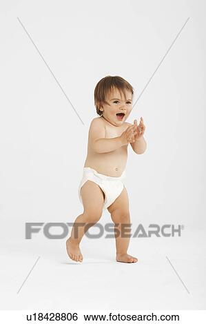 Stock Photograph - Excited toddler taking first steps in white studio. Fotosearch