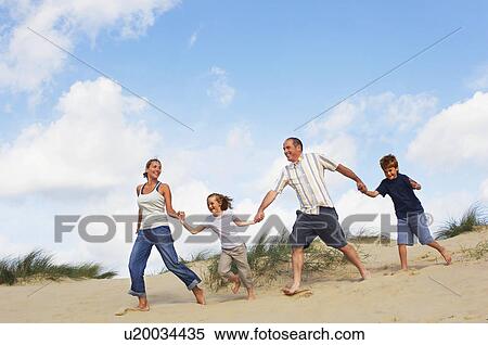 Family holding hands and running down sand dune on beach View Large Photo Image Stock Photography - Family holding hands and running down sand dune on beach. Fotosearch