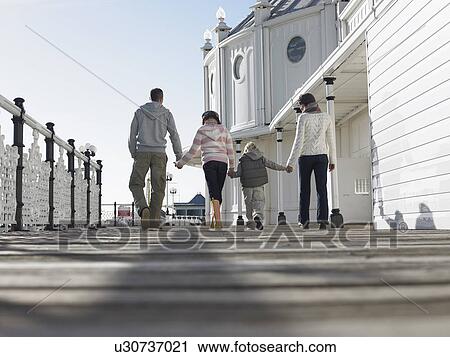 Family holding hands, walking along pier, back view, low angle view View Large Photo Image Stock Image - Family holding hands, walking along pier, back view, low angle view. Fotosearch