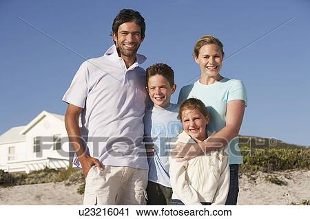 Family standing on beach smiling, beach house behind View Large Photo Image Stock Image - Family standing on beach smiling, beach house behind. Fotosearch