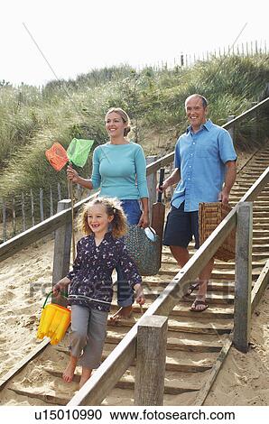 Stock Image - Family walking down wooden steps onto beach. Fotosearch