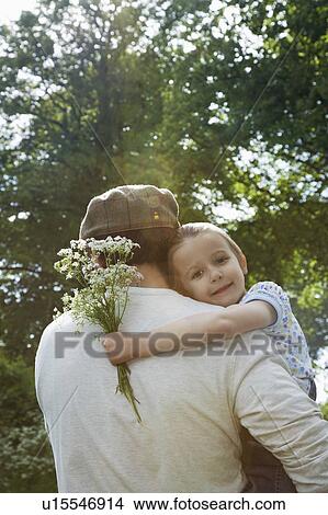 Father and daughter (5-6) embracing in countryside, daughter carrying bunch of flowers View Large Photo Image Picture - Father and daughter (5-6) embracing in countryside, daughter carrying bunch of flowers. Fotosearch