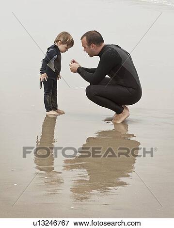 Father and son crouch in wet sand View Large Photo Image Stock Photo - Father and son crouch in wet sand. Fotosearch