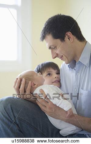 Stock Photo - Father and son sit with two week old newborn baby. Fotosearch