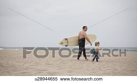 Father and son walk towards sea carrying surfboard View Large Photo Image Stock Photography - Father and son walk towards sea carrying surfboard. Fotosearch