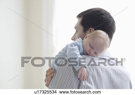 Picture - Father holds newborn on shoulder. Fotosearch