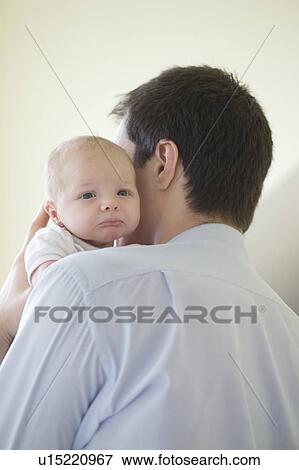 Stock Photo - Father holds two week old newborn on his shoulder. Fotosearch