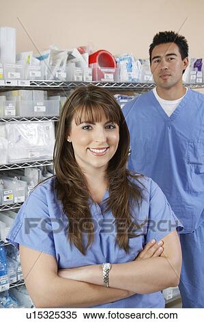 Stock Photography - Female and male nurse standing by shelves with medical supply, portrait. Fotosearch