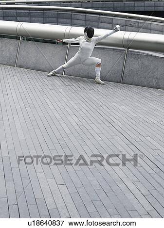 Stock Photo - Female fencer lunging, outdoors. Fotosearch